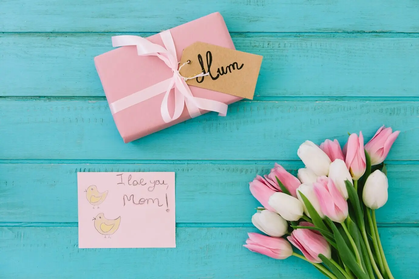 Schriftzug „Ich liebe dich, Mama“ mit Tulpen und Geschenk.